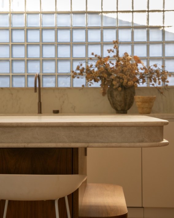 Stone benchtop with dried flowers in front of a glass-block window
